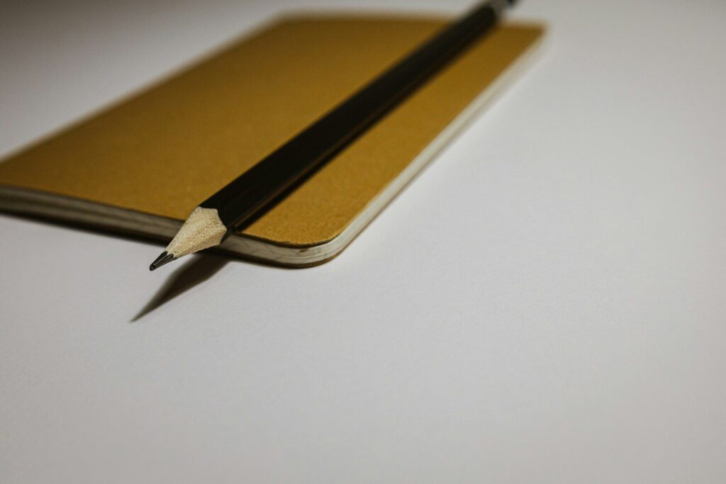 Ołówek leżący na żółtym notesie jako symbol perfekcjonizmu i dbałości o szczegóły